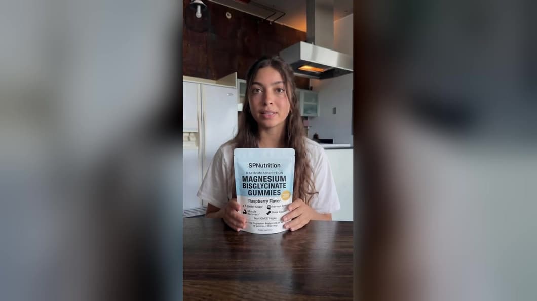 Presenter at a kitchen table holding a pack of SPNutrition Magnesium Bisglycinate Gummies